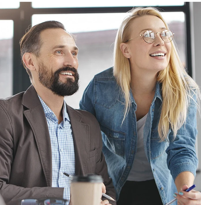 Deux collègues discutent et sourient au bureau.